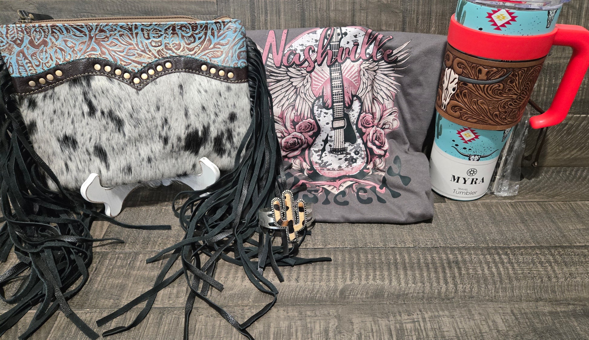 Cowhide leather bag with fringe, 'Nashville' t-shirt with guitar design, and Myra water bottle